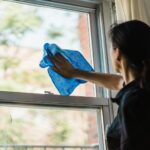 Woman in Black Shirt Holding Blue Textile Near Window